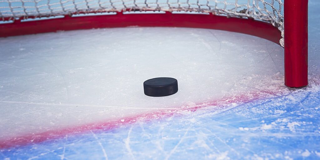 Hockey puck crossing red goal line. Close view